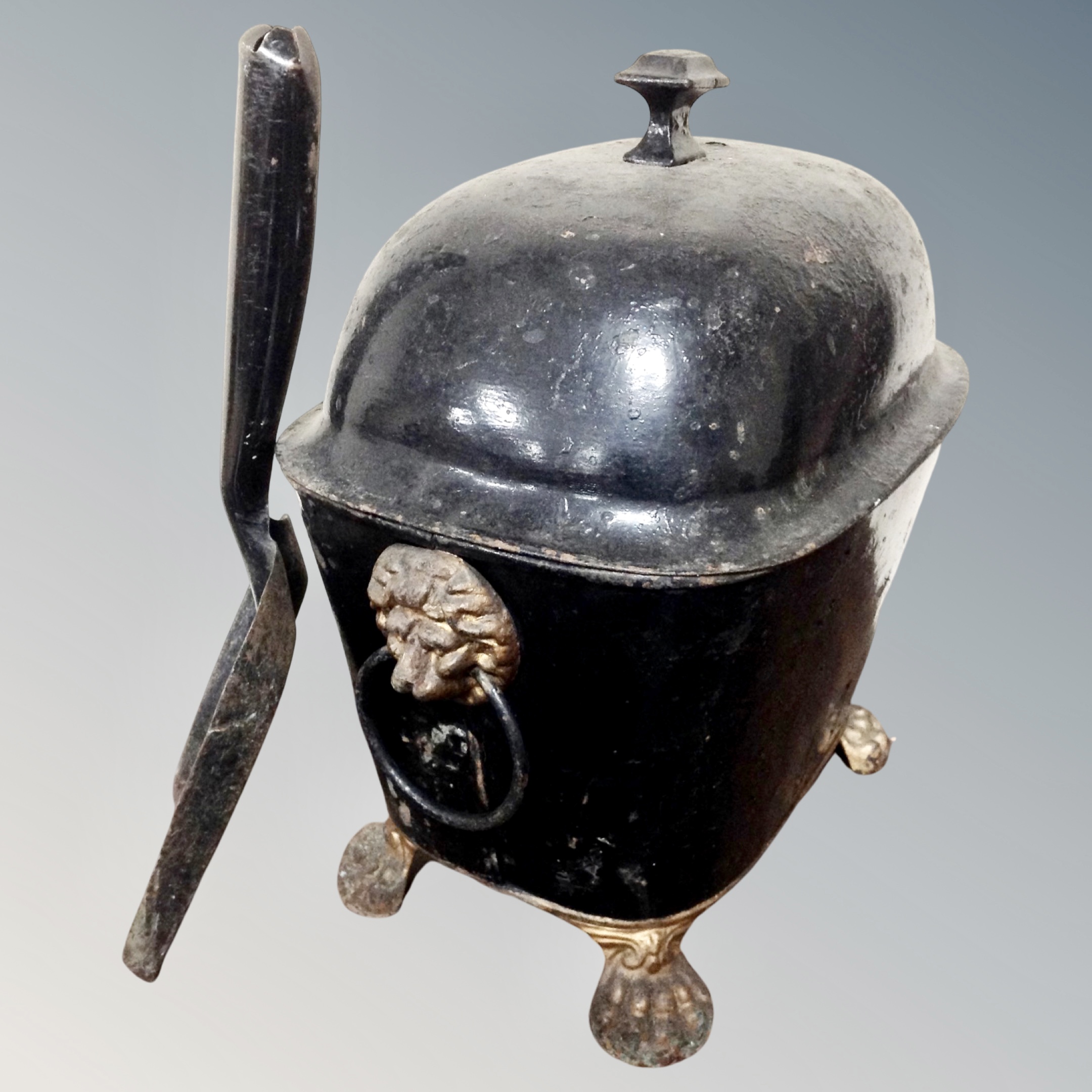 A Victorian toleware coal receiver with lion mask handle and paw feet, with shovel.