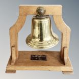 A brass ship's bell on oak stand with presentation plaque inscribed 'Presented by Rotarian H