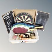 A dart board in cabinet and a box of darts, fishing equipment,