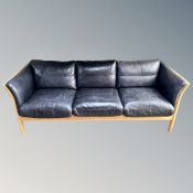 A Scandinavian wood framed dark blue leather three seater settee