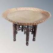 An Eastern copper topped folding table on circular stand,