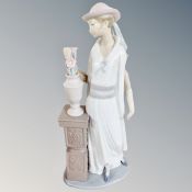 A Lladro figure of a lady by an urn of flowers