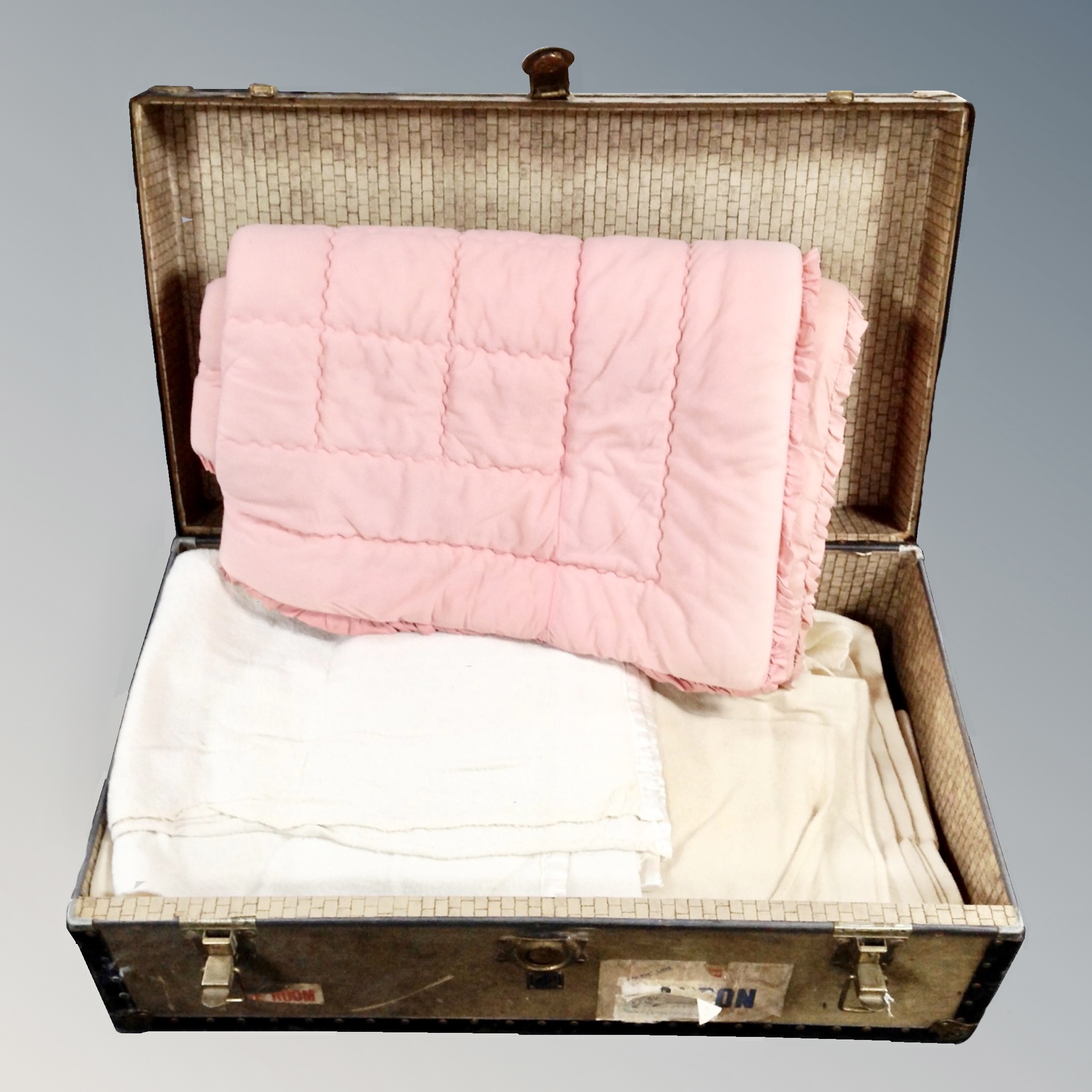 A vintage metal bound trunk containing assorted blankets