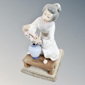 A Lladro figure of a geisha arranging flowers in a vase