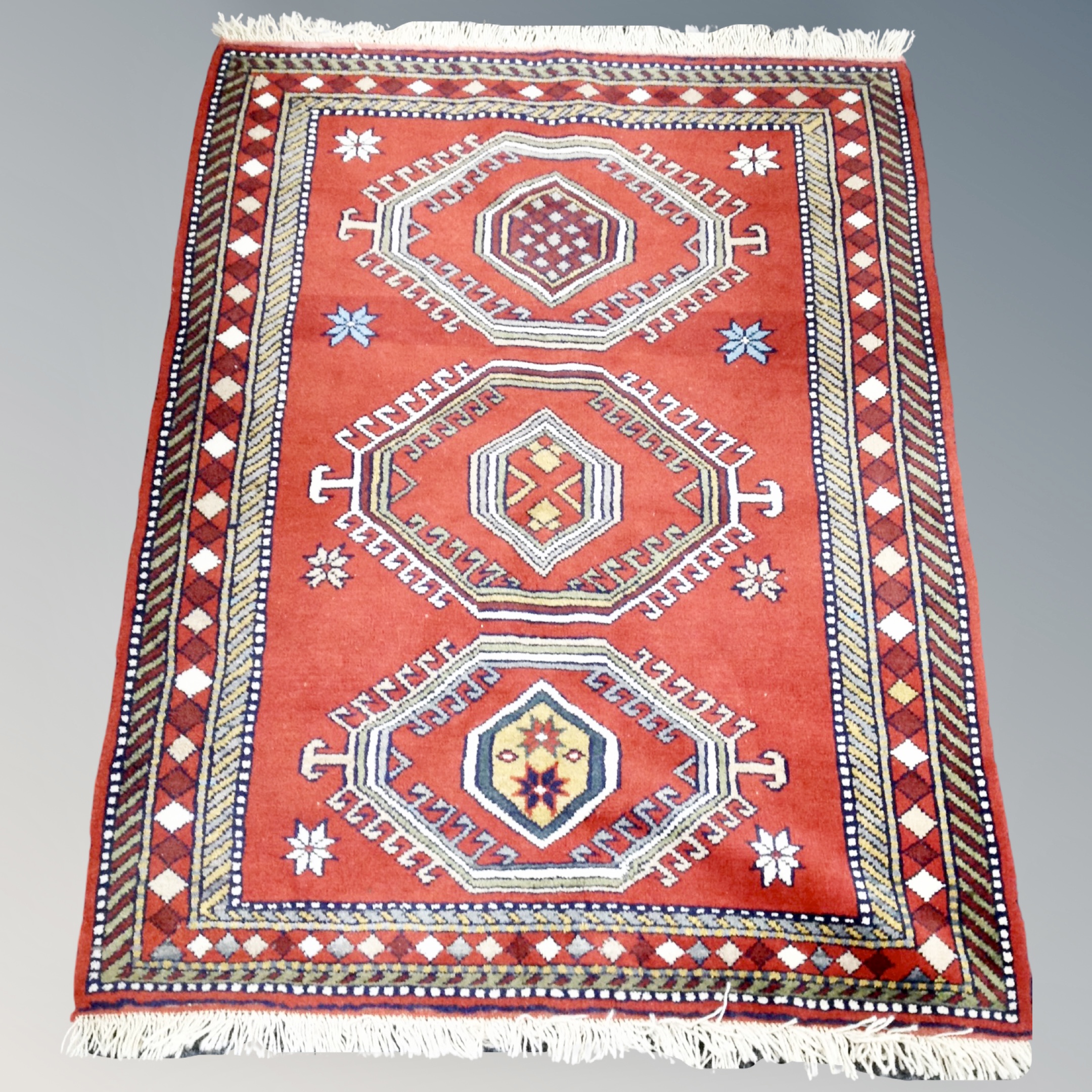 A Causcasian design rug, on red ground,