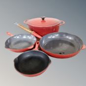 A cast iron Le Creuset oval lidded cooking pot and three graduated cast iron frying pans
