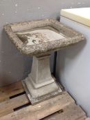 A weathered concrete square topped bird bath on pedestal
