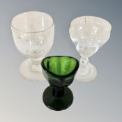 A green eye bath and two further antique glasses,