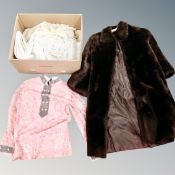 A box of faux fur coat, assorted table linen,