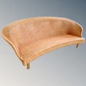 A shaped Art Deco style wicker settee on wooden legs