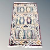 A fringed woolen rug of geometric design,