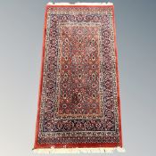 A Persian-design rug on red ground,