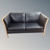 A Scandinavian wood framed black leather two seater settee