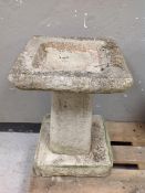 A weathered concrete square topped bird bath on pedestal