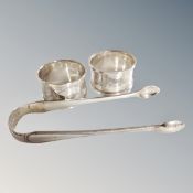 A pair of silver sugar tongs with London hallmarks and a pair of napkin rings