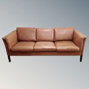 A Scandinavian brown leather three seater settee,