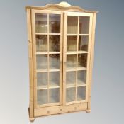 A pine double door glazed bookcase on bun feet