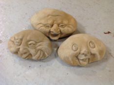 Three graduated concrete happy face stones