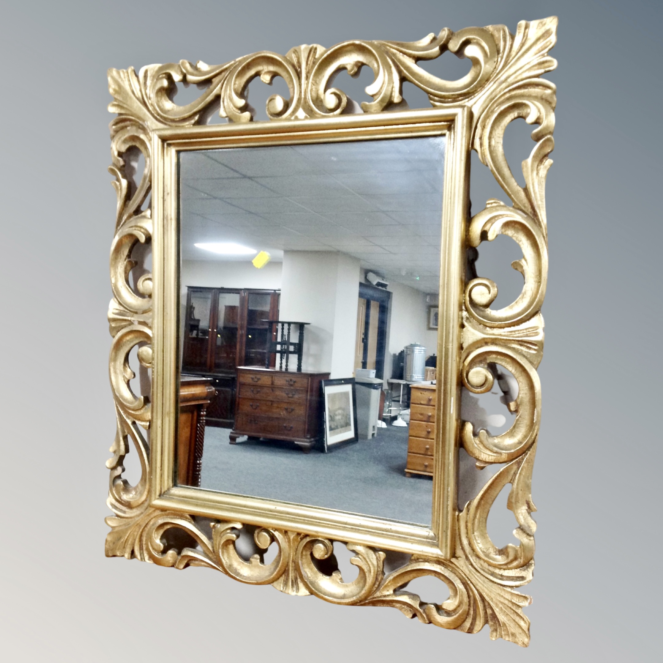 A decorative gilt period- style wall mirror in swept frame