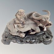 A Chinese carved hardwood figure of a man astride a water buffalo on carved hardwood stand