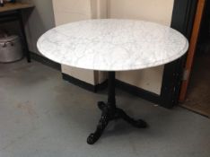 A circular white marble topped bistro table on cast iron three way pedestal