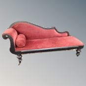 An ebonised chaise longue in red upholstery