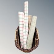 A vintage wicker twin-handled log basket containing four window blinds