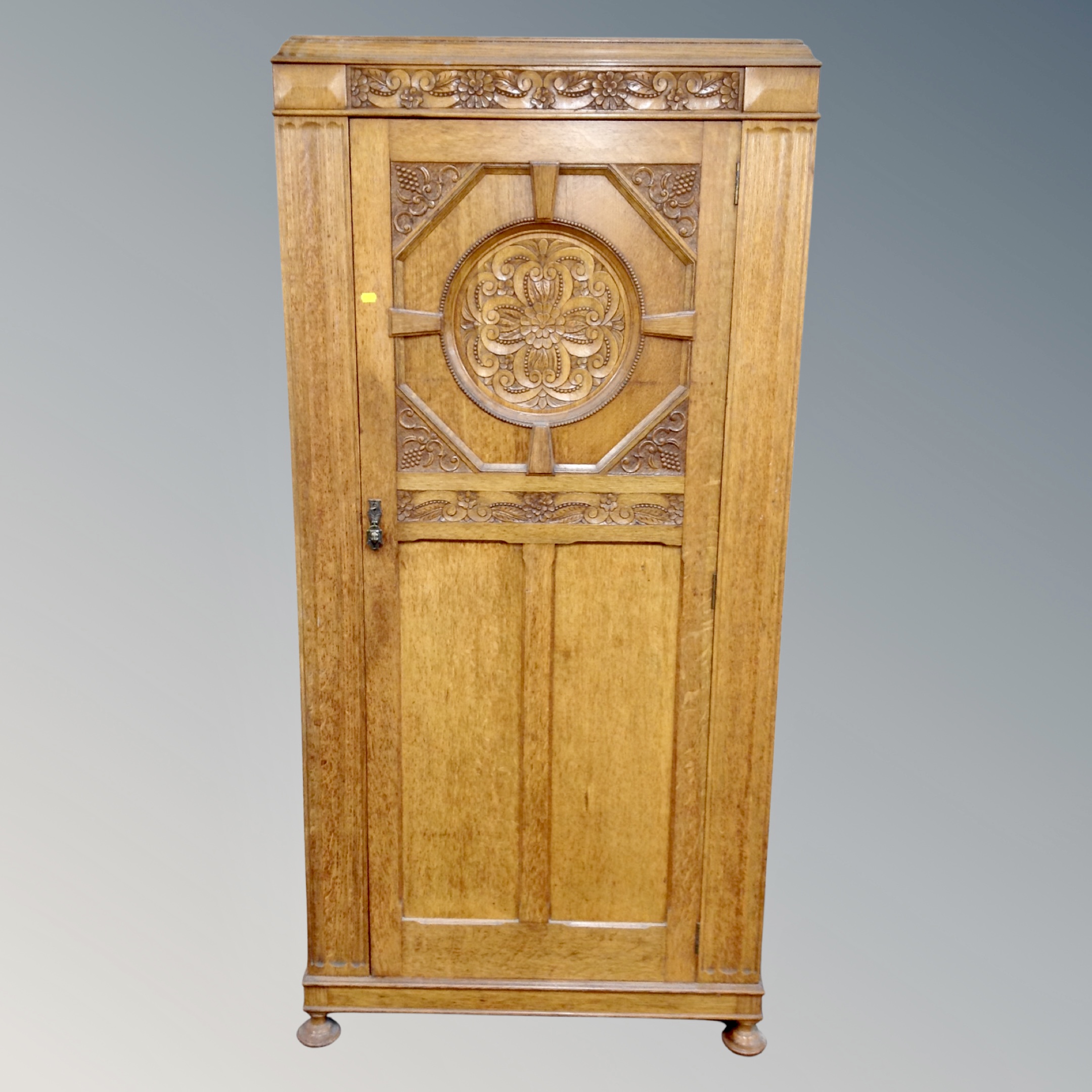 A 1920's carved oak single door wardrobe,