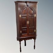 A George III panelled oak corner cabinet on stand