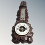 A Black Forest style carved barometer surmounted by an owl