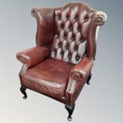 A Chesterfield oxblood buttoned leather wingback armchair