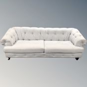 A Chesterfield settee upholstered in light grey fabric,