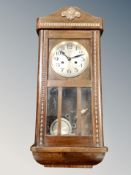 An Edwardian wall clock with pendulum and key.