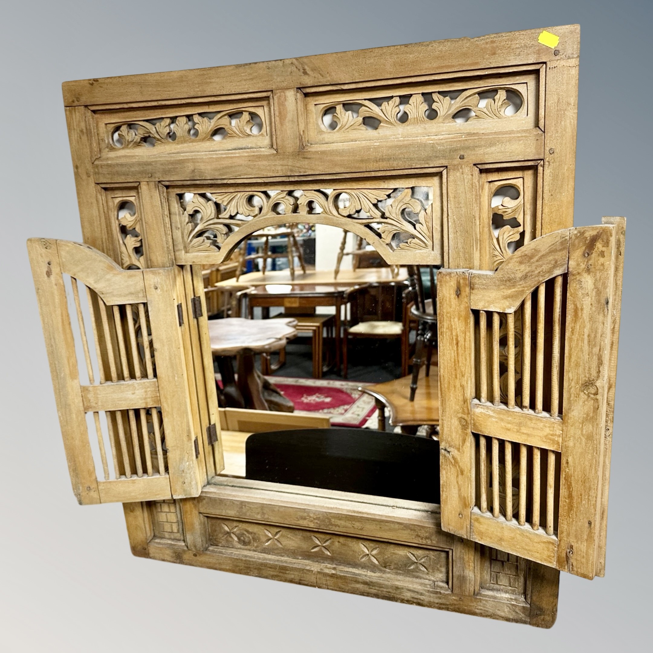 A carved Eastern mirror with shutter doors,
