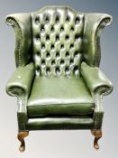 A green buttoned leather Chesterfield wingback armchair