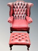 A red leather Chesterfield buttoned wing armchair with matching footstool