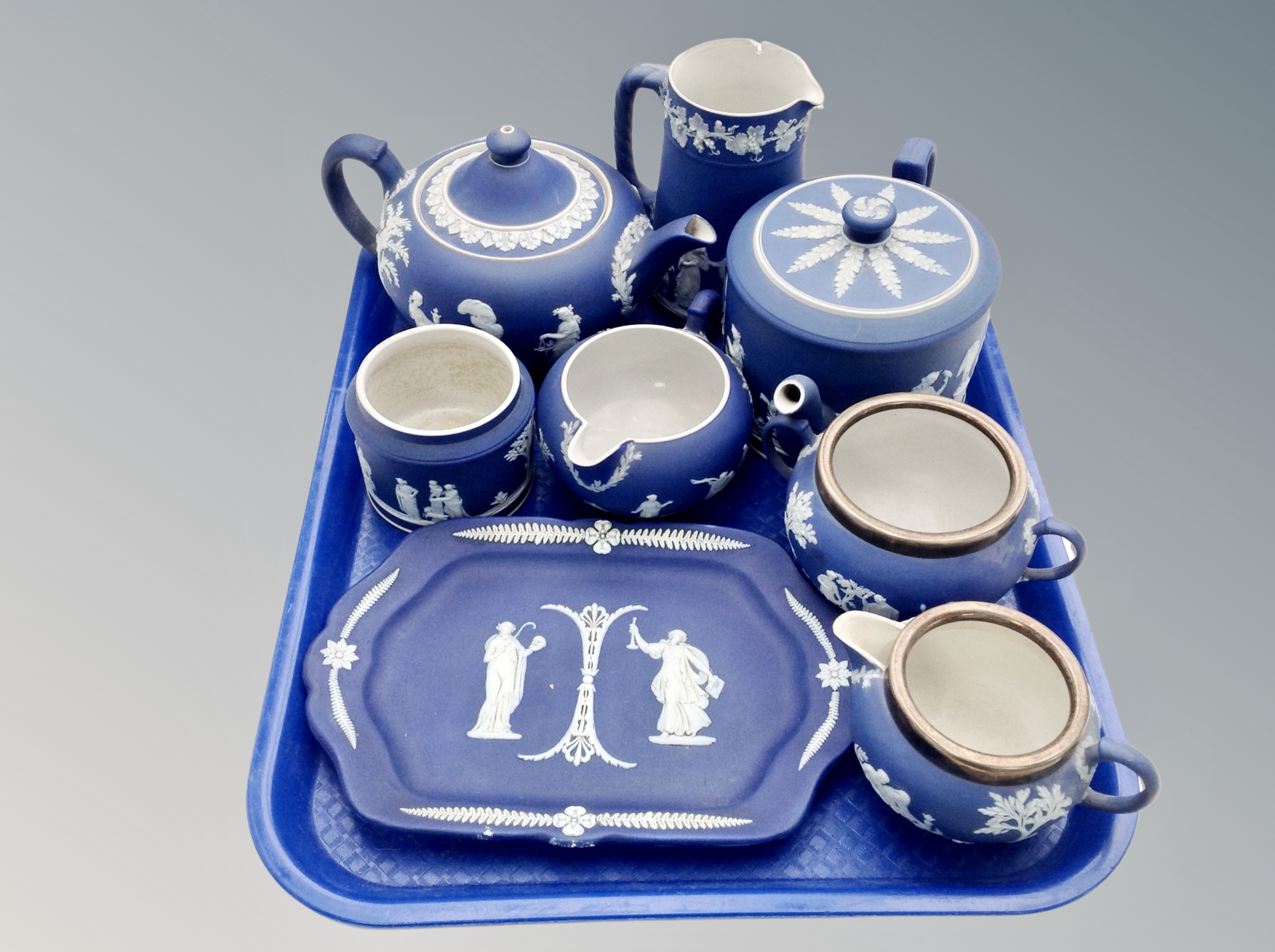 Two trays of Wedgwood blue and white jasper ware : teapots, biscuit barrel with plated lid,