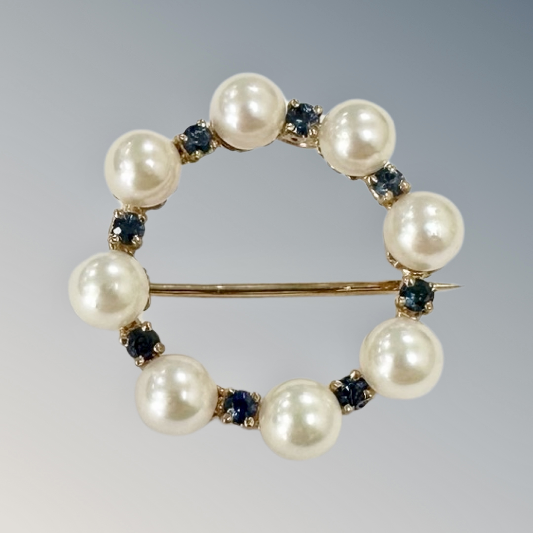 A 9ct gold sapphire and seed pearl circular brooch, diameter 2.