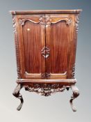 A reproduction mahogany double door cabinet on raised legs,