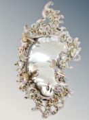 A Dresden porcelain cartouche-shaped wall mirror decorated with putti,