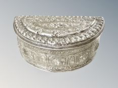 An Indian white metal demi-lune trinket box with all-over embossed decoration, width 9.