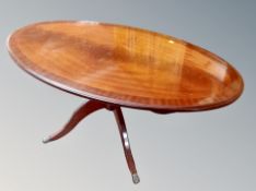 A contemporary mahogany oval pedestal coffee table on brass capped feet