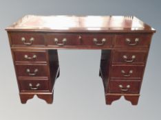 A reproduction mahogany twin pedestal writing desk fitted with nine drawers, tooled leather top,