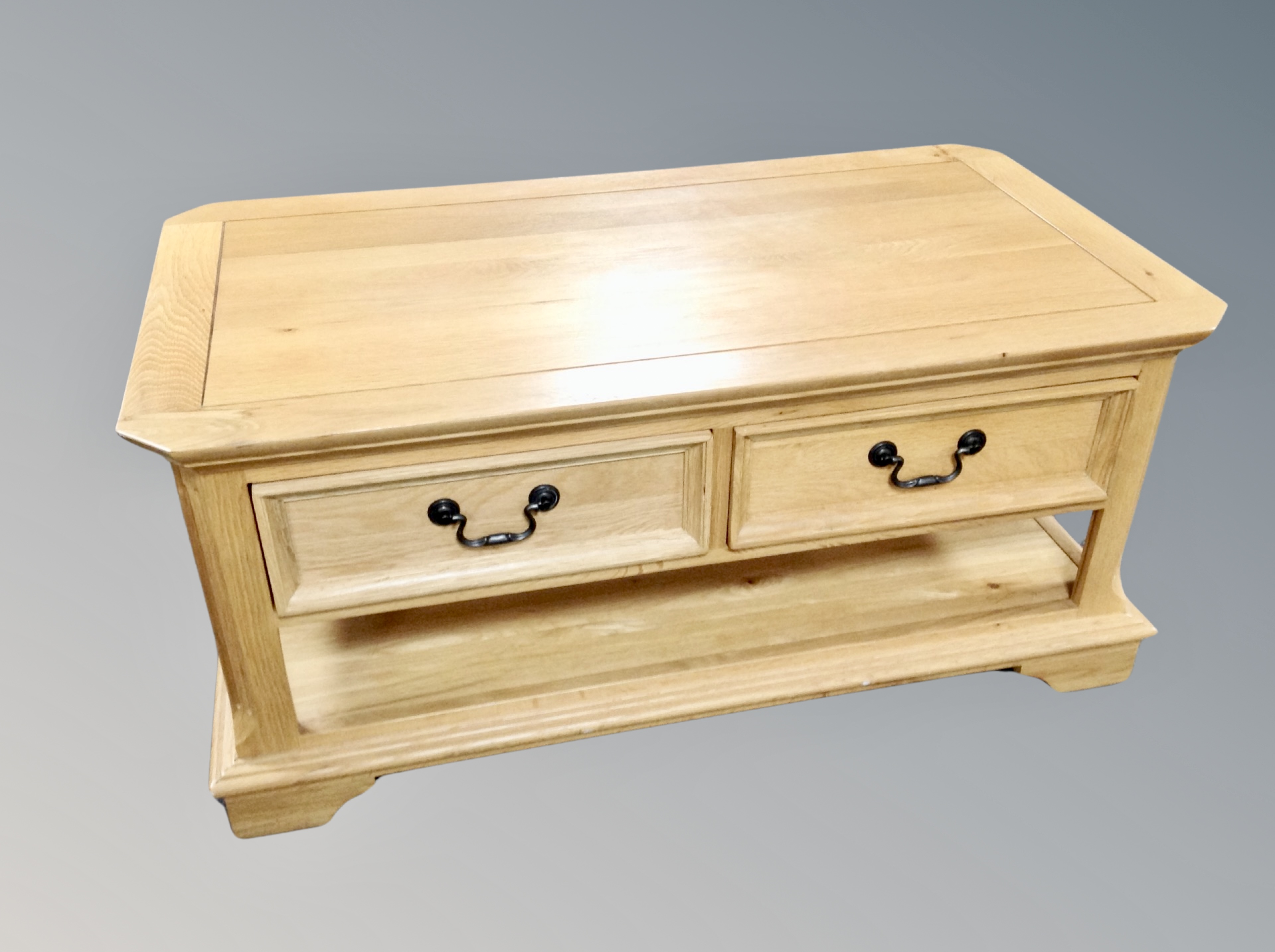 A contemporary oak shaped coffee table fitted with drawers