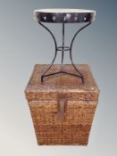 A wicker laundry basket together with circular wrought iron wine table