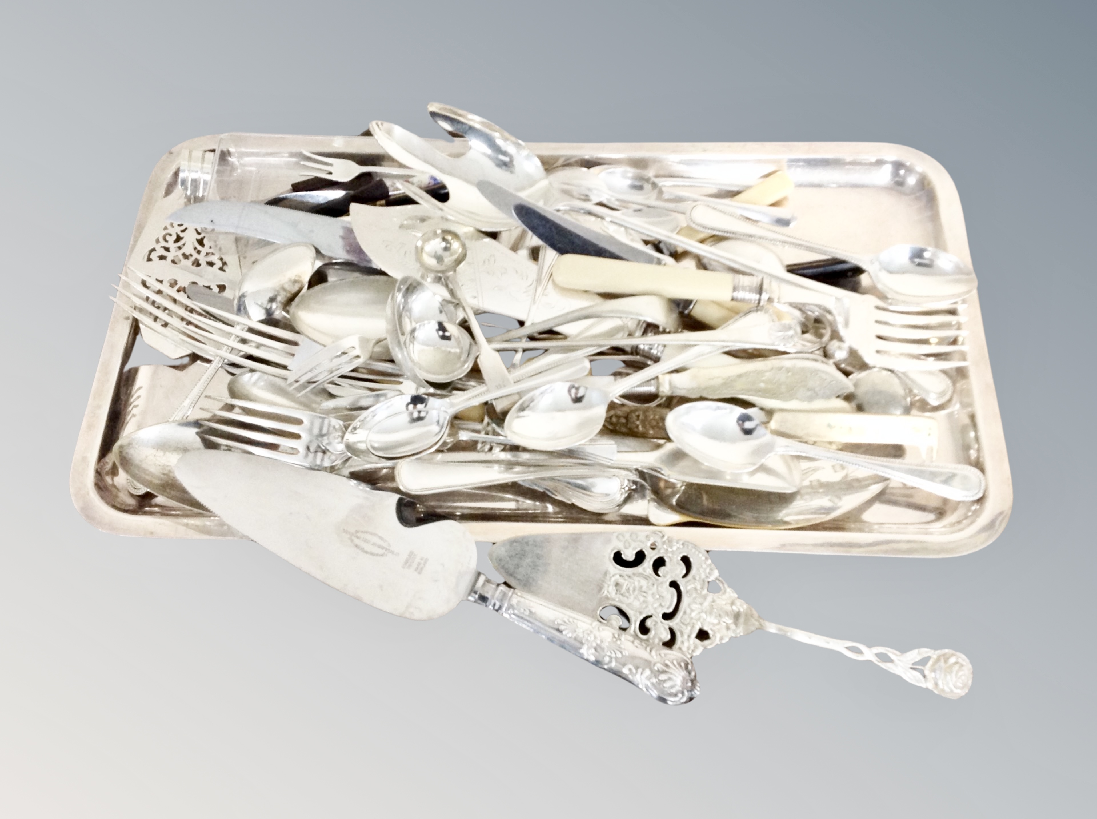 A plated tray of cutlery, cake slice, servers, silver handled server,