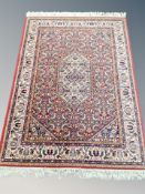 A machined Persian-design rug on red ground,