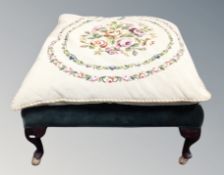 An oversized square topped footstool upholstered in green dralon with large tapestry cushion