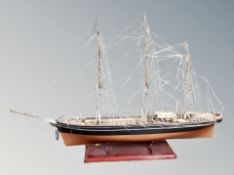A model of a three masted ship on wooden stand