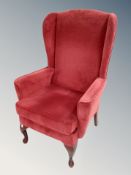 A fireside wingback armchair in red dralon
